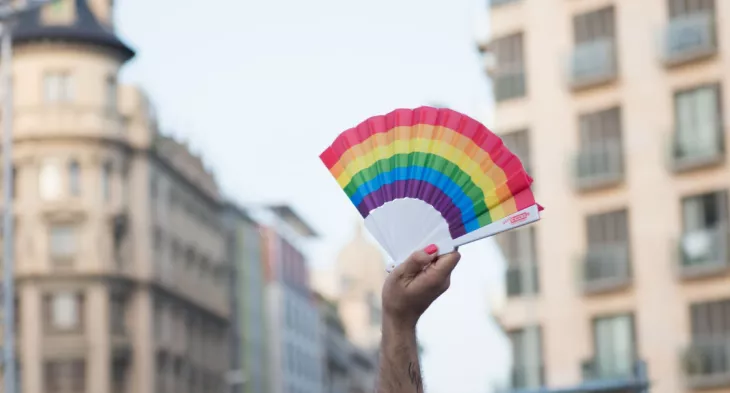 Mano sosteniendo un abanico con la bandera LGTBI