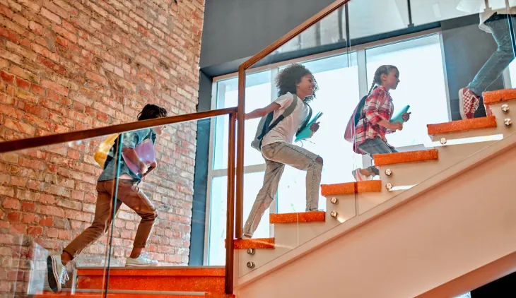 Three girls going up the interior stairs of a school