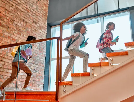 Three girls going up the interior stairs of a school