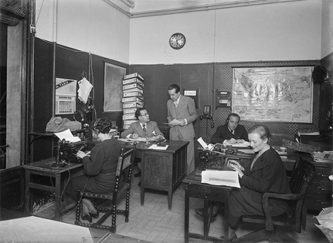 Ràdio Barcelona newsroom, 1936. In the foreground on the right, Maria del Carme Nicolau writing the news. On the left, a secretary types what is dictated to her over the phone. © Alexandre Merletti / Institut d’Estudis Fotogràfics de Catalunya