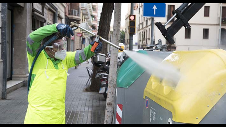 A cleaning service worker washes water under pressure in containers located in Plaça de Gal·la Placídia and surroundings 