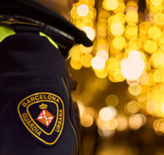 A Guardia Urbana oficer patrols a street in Barcelona illuminated with Christmas motifs