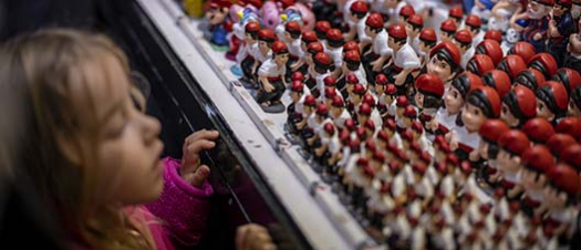 Una niña mira embobada a los caganers expuestos en una parada de la Feria de San Lucía