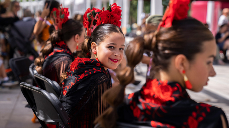 In the foreground, a smiling young participant in the show “Flamenco i flores” in the district of Sant Andreu