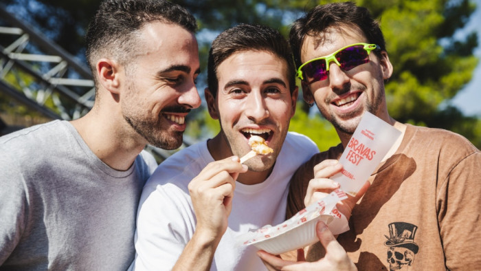 Tres jóvenes comen patatas bravas en el Mahou Bravas Fest Barcelona